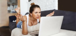 Confused women on sofa with laptop.