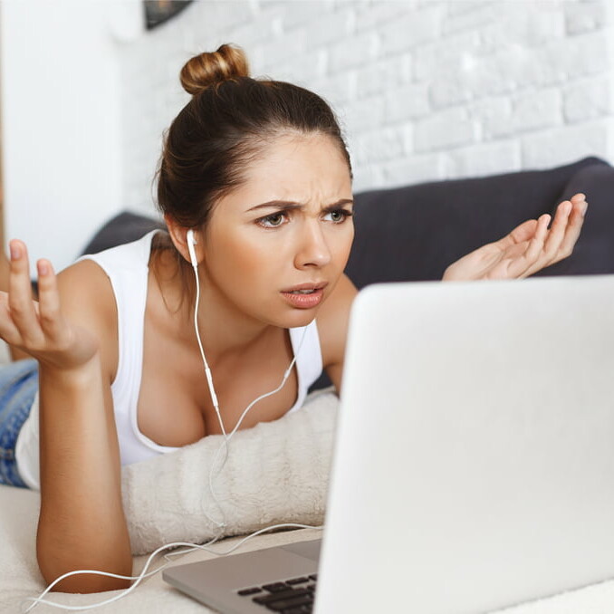 Confused women on sofa with laptop.