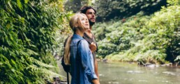 Hiker couple standing by stream in the woods