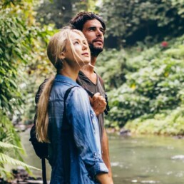 Hiker couple standing by stream in the woods