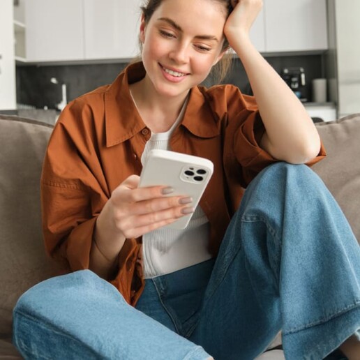 Woman resting on couch reading messages on mobile phone.
