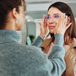 Optician helping customer with spectacles fitting
