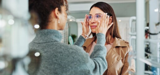 Optician helping customer with spectacles fitting