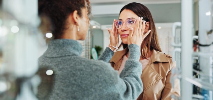 Optician helping customer with spectacles fitting